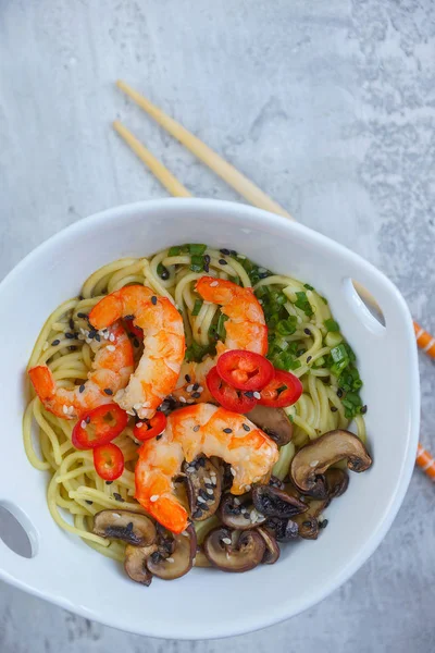 Hot asian wok noodles with shrimps and mushrooms, Ramen, Gray background, Close-up