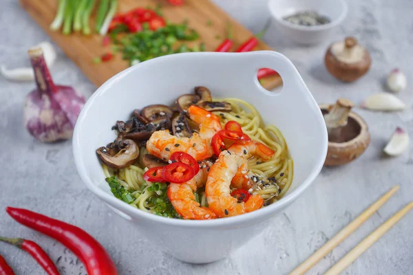 Hot asian wok noodles with shrimps and mushrooms, Preparation ramen, Gray background, Closeup