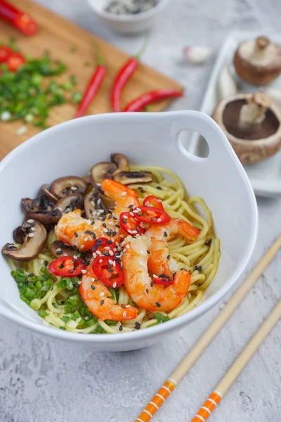 Hot asian wok noodles with shrimps and mushrooms, Preparation ramen, Gray background, Closeup