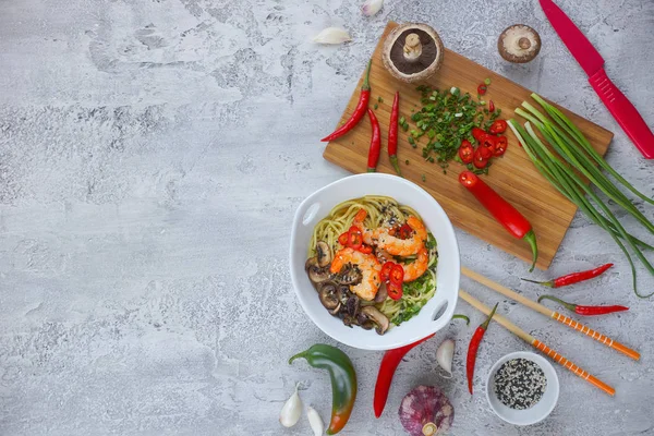 Hot asian wok noodles with shrimps and mushrooms, Preparation ramen, Gray background, Copy space