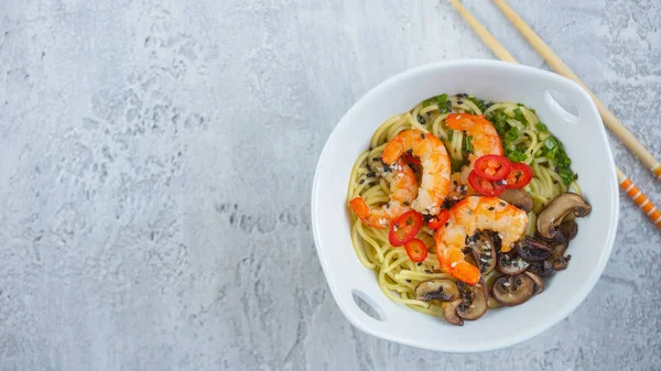 Hot asian wok noodles with shrimps and mushrooms, Ramen, Gray background, Copy space