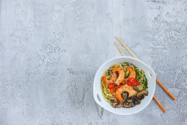Hot asian wok noodles with shrimps and mushrooms, Ramen, Gray background, Copy space