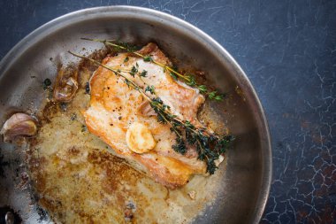 Metal bir tavada kekikli domuz bifteği pişirme.