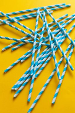 Sarı arka plandaki kokteyller için mavi pipetler