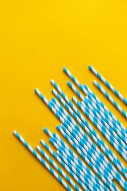 Sarı arka plandaki kokteyller için mavi pipetler