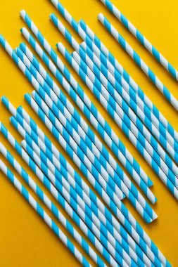 Sarı arka planda mavi kokteyl pipetleri