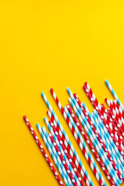 Sarı arka planda çok renkli kokteyl pipetleri