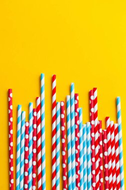 Sarı arka planda çok renkli kokteyl pipetleri