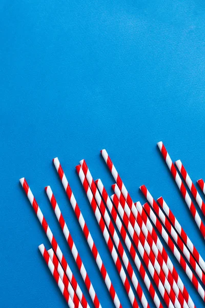 Red cocktail straws on a blue background