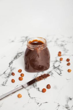 Mermer beyaz bir masada bir kavanoz lezzetli çikolata ezmesi.