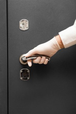 Tıbbi eldivenli bir erkek, kapı kolunu tutar.