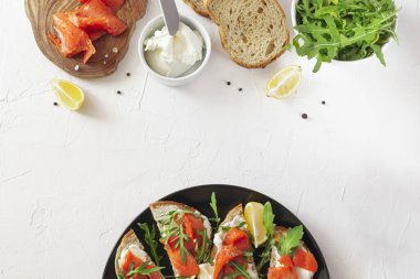 Tabakta somonlu sandviç ve yemek malzemeleri.