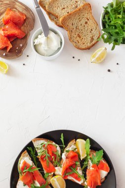 Tabakta somonlu sandviç ve yemek malzemeleri.