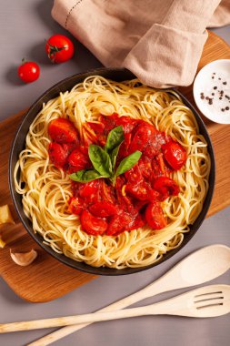 Domatesli makarna ve bir tavada fesleğen peçete ve gri arka planda