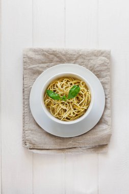 Beyaz tabakta, arka planda pesto makarna. Üst görünüm