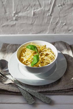 Beyaz bir kasede, beyaz bir arka planda, güneş ışığında makarna.