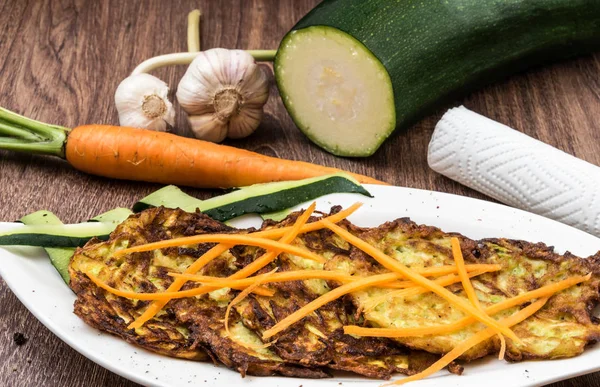 Жареные цуккини с травами и чесноком на белой тарелке украшены тертой морковью — стоковое фото