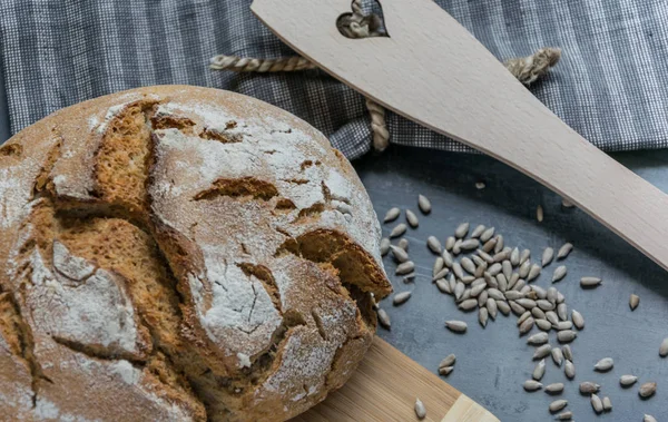 Свежий домашний мясной хлеб с семечками подсолнечника на сером фоне с сине-серым полотенцем — стоковое фото