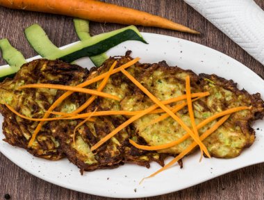 Kızarmış patates ve kabak krep. Sarımsak ve otlar ile terbiyeli. Rendelenmiş havuç dekore edilmiş