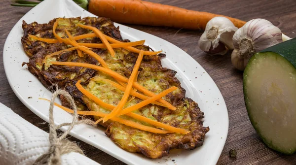 Gebratene Zucchini und Kartoffelpuffer. gewürzt mit Knoblauch und Kräutern. dekorierte geriebene Möhren — Stockfoto
