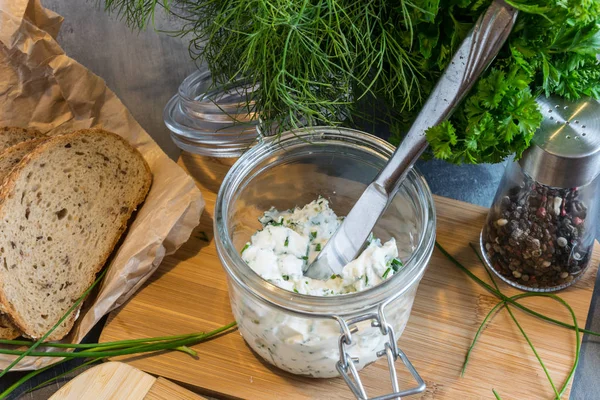 Ev yapımı ekmek, kaymak peyniri, ricotta ve bitkilerle ahşap bir kesim tahtasından. Yeşil otlarla süslenmiş. 