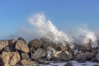 Denizde fırtına. Büyük dalgalar. Su sıçratıyorum. Suyun gücü. Denizde taş yığınları. Kıyıya yakın bir yerde dalgalı su. Fırtınalı Akdeniz. İspanya tatil köyü. Güçlü rüzgar.
