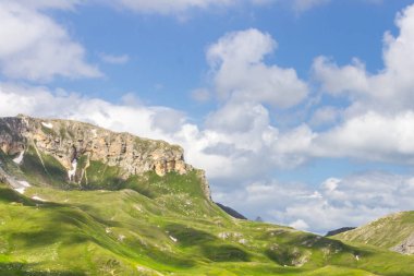 Avusturya Alpleri. Karlı dağ zirveleri. Grossglockner Dağı. Doğanın görkemi. Alp yolu. Dağ manzarası. Tepelerde yeşil çimenler. Kayaların arasındaki ormanlar. Avrupa 'da yürüyüş.