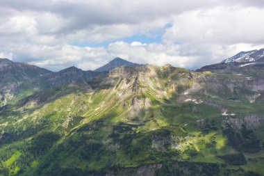 Avusturya Alpleri. Karlı dağ zirveleri. Grossglockner Dağı. Doğanın görkemi. Alp yolu. Dağ manzarası. Tepelerde yeşil çimenler. Kayaların arasındaki ormanlar. Avrupa 'da yürüyüş.