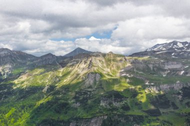Avusturya Alpleri. Karlı dağ zirveleri. Grossglockner Dağı. Doğanın görkemi. Alp yolu. Dağ manzarası. Tepelerde yeşil çimenler. Kayaların arasındaki ormanlar. Avrupa 'da yürüyüş.