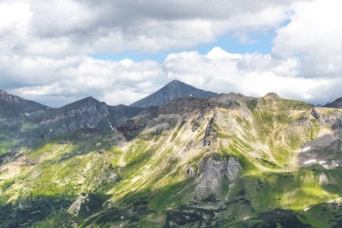 Avusturya Alpleri. Karlı dağ zirveleri. Grossglockner Dağı. Doğanın görkemi. Alp yolu. Dağ manzarası. Tepelerde yeşil çimenler. Kayaların arasındaki ormanlar. Avrupa 'da yürüyüş.