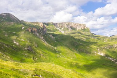 Avusturya Alpleri. Karlı dağ zirveleri. Grossglockner Dağı. Doğanın görkemi. Alp yolu. Dağ manzarası. Tepelerde yeşil çimenler. Kayaların arasındaki ormanlar. Avrupa 'da yürüyüş.