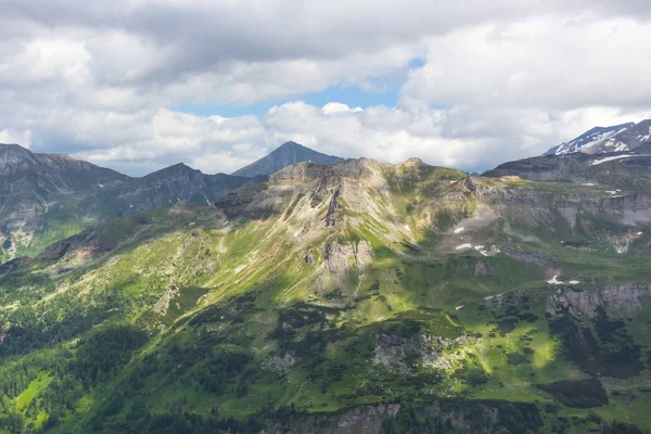 Avusturya Alpleri. Karlı dağ zirveleri. Grossglockner Dağı. Doğanın görkemi. Alp yolu. Dağ manzarası. Tepelerde yeşil çimenler. Kayaların arasındaki ormanlar. Avrupa 'da yürüyüş.