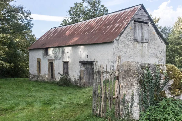 Abandoned house. Empty rural barn. Country landscape. The old farm. Window opening without a frame. Shabby facade. The ruined building. Old tiled roof.