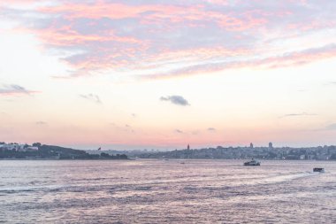 Deniz limanı. Boğaz Boğazı. İstanbul manzarası. Sahil tatil köyü. Suyun üstünde feribot. Denizde bir gemi. Gün batımı gökyüzü. Gökyüzü gradyanı. İstanbul 'da deniz manzarası. Şehir ufukta görünüyor. Pembe ve mavi gölgeler.