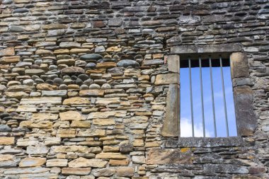 Taş duvar. Tarihi bir binanın ön cephesinin korunması. Boş pencere açılıyor. Ortaçağ Avrupa 'sı. Mahvolmuş bir ev. Demir kapı. Antik bir kalenin duvarı. Taş kale.