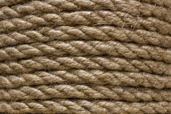 Thick rope. Rope in the interior decoration. Natural jute. Loft style element. Jute background. Coarse thread close-up. Coiled rope. Canvas for the point of cat\'s claws.