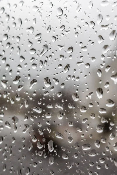 Spring rain. May thunderstorm. Raindrops on the glass. The texture of the drops. Wet window. Chill day. Inclement weather. Torrential rain. View of the world from the window.