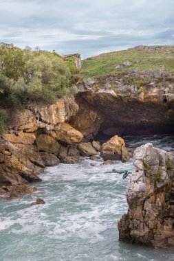 Yüzücünün bakır anıtı. Uçurumdan denize atla. Sahilde bir mağara. Kayalık dağlarda dalgalar. Tehlikeli kayalar. İspanya 'nın doğası. Fırtınalı dalgalar arasında kayalar ve kaldırımlar. Vahşi deniz doğası. 