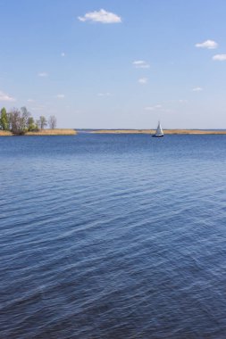 Nehirde ada ve yat. Dinyeper 'da yelkenli bir tekne. Ukrayna 'nın doğası. Resimli bir manzara. Güzel göl manzarası. Baharda kamp yapmak. Suda küçük dalgalanmalar. Rahatlık adacığı.