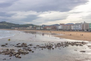 Deba tatil köyünün geniş plajı. İspanya 'da tatiller. Sörfçülere yer açın. Bilinmeyen sörfçüler. Suda son derece eğlenceli. Su sporu. Yavaşça eğimli kıyı.