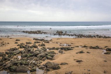 Deba tatil köyünün geniş plajı. İspanya 'da tatiller. Sörfçülere yer açın. Bilinmeyen sörfçüler. Suda son derece eğlenceli. Su sporu. Yavaşça eğimli kıyı.