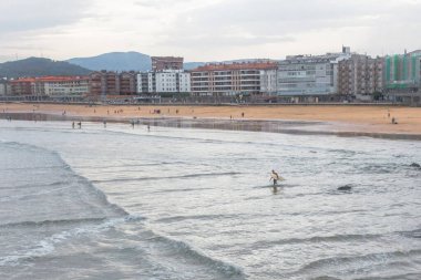 Deba tatil köyünün geniş plajı. İspanya 'da tatiller. Sörfçülere yer açın. Bilinmeyen sörfçüler. Suda son derece eğlenceli. Su sporu. Yavaşça eğimli kıyı.