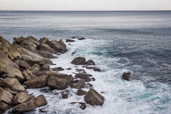 Stormy sea. Wave splash. The wave beats on the shore. Sea spray and foam around the stone. Water element. Storm at sea. Ebbs and flows. Power of nature.