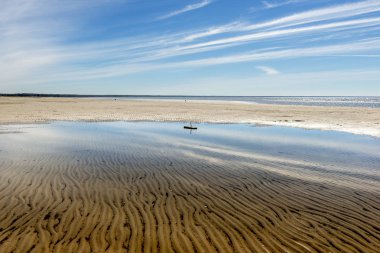 Baltık Denizi, boş bir plaj. Su gökyüzünün yansıması. Kum su tarafından oyulmuş çizgileri