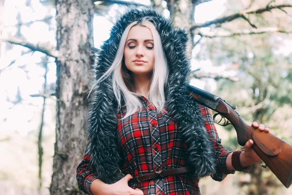 Beautiful woman hunter in forest with gun