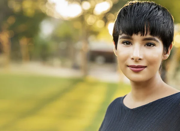 Portrait of modern woman with short hair in natural park setting. Sun setting behind her. — Stock Photo, Image