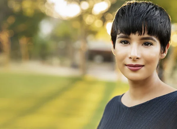 Retrato de mujer moderna con el pelo corto en el entorno del parque natural. Puesta de sol detrás de ella . — Foto de Stock