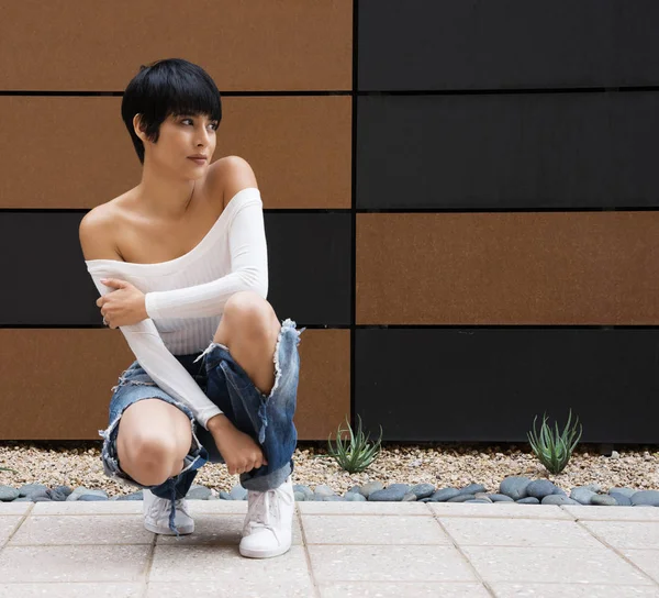 Beautiful young woman wearing ripped denim jeans and off shoulder white top — Stock Photo, Image