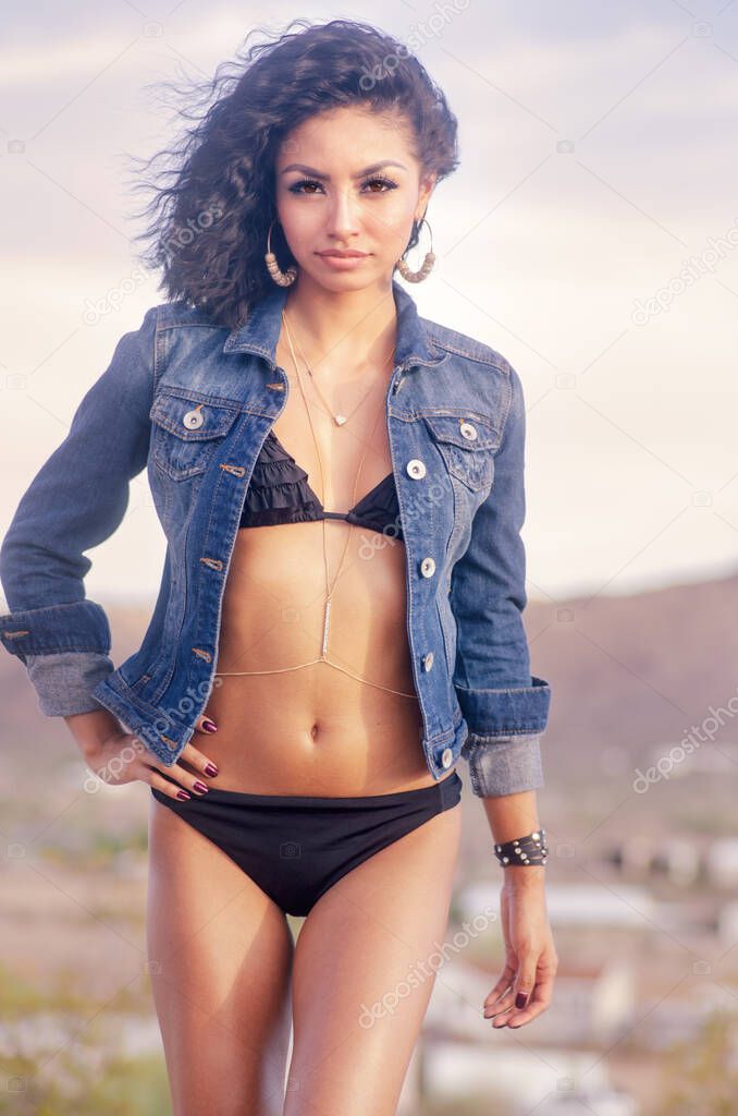 Beautiful woman with fuzzy curly hair wearing denim jacket and bikini, CA,USA