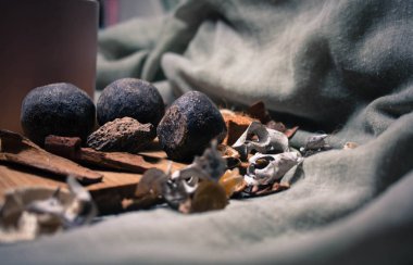 Tarçınlı doğal kakao topları ve ahşap tezgahta diğer baharatlar gri arka planda pembe bir fincanın yanında.